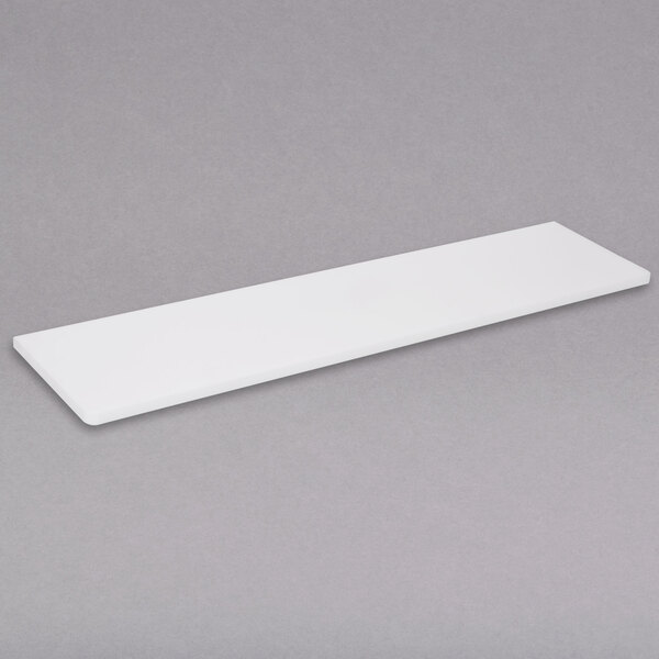 A white rectangular APW Wyott cutting board on a gray surface.
