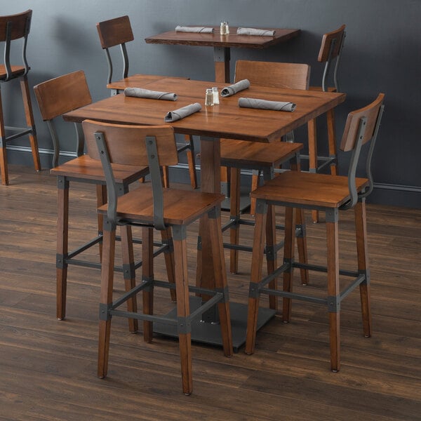 A Lancaster Table & Seating wooden bar height table with four barstools.