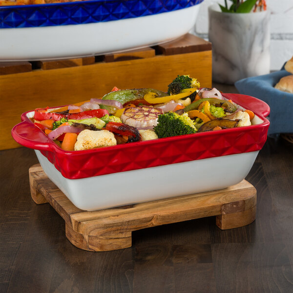 A red and white Tuxton rectangular casserole dish filled with vegetables.