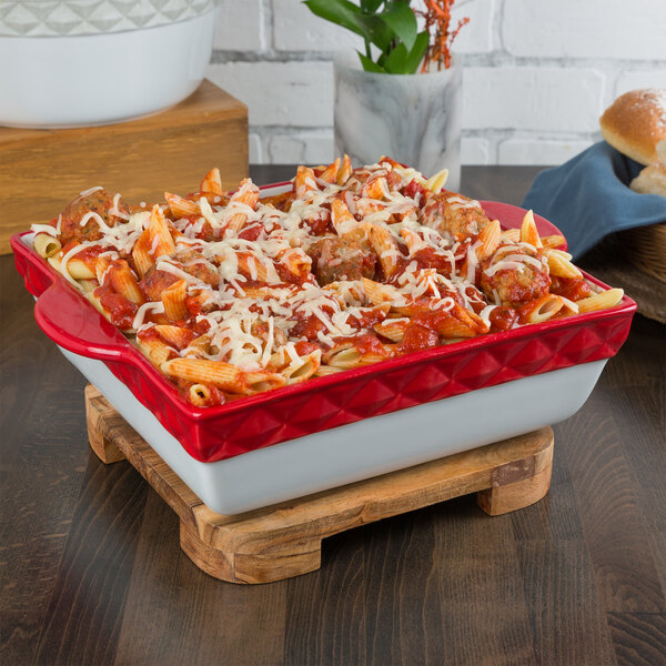 A Tuxton cayenne band square china casserole dish filled with pasta and meatballs.
