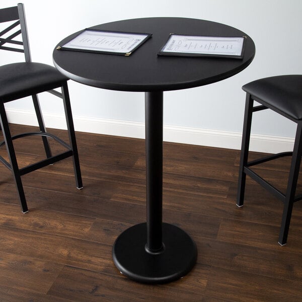 A Lancaster Table & Seating black bar height table with a reversible cherry/black round table top and round cast iron base.