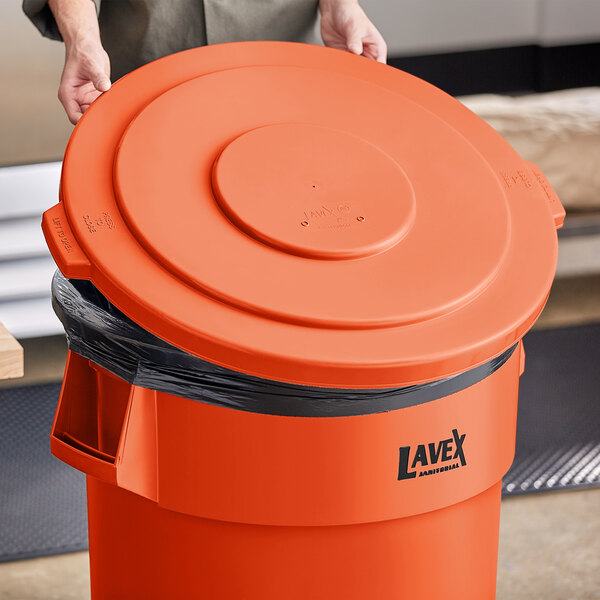A person opening a Lavex orange high visibility trash can lid.