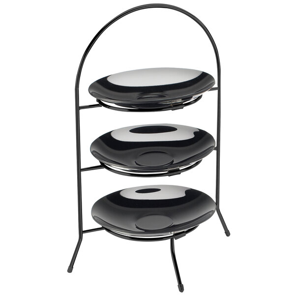 A black iron three tier bowl and plate display with white plates on top.