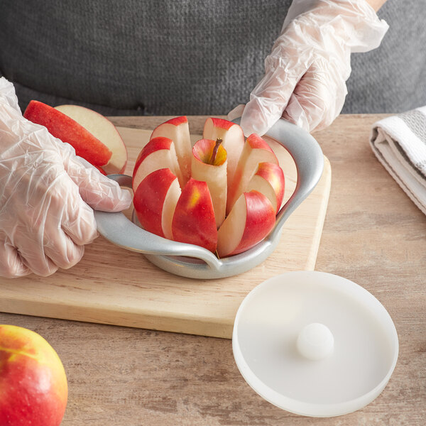 A person wearing gloves using a Choice heavy duty apple corer/slicer to cut an apple.