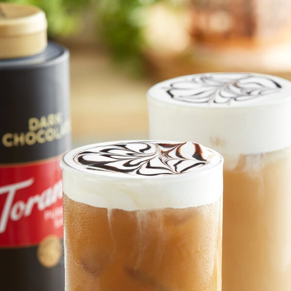 Two glasses of iced coffee with Torani Dark Chocolate Sauce on a table.