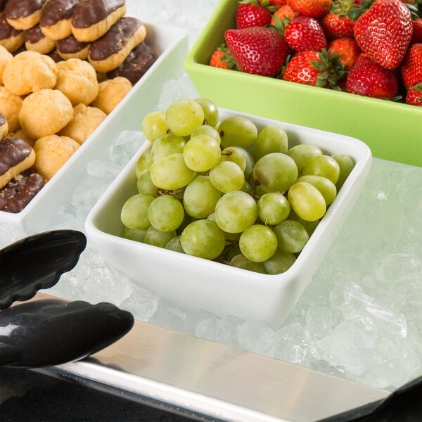 A G.E.T. Enterprises white resin-coated aluminum square bowl with strawberries and grapes on ice.