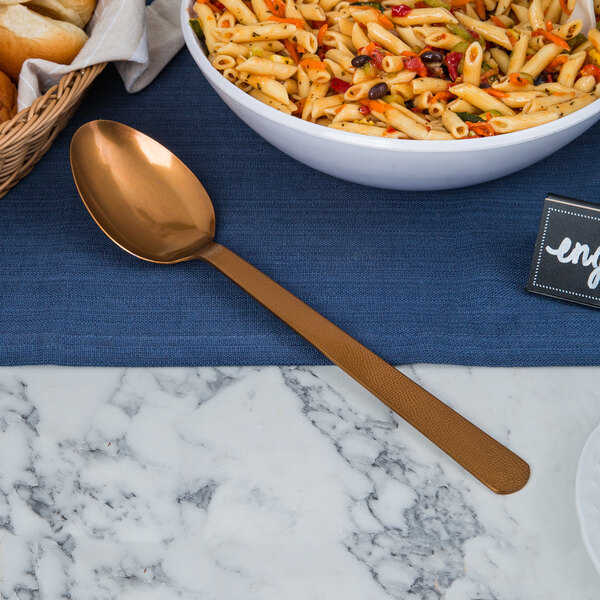 A bowl of pasta with a spoon on a table.