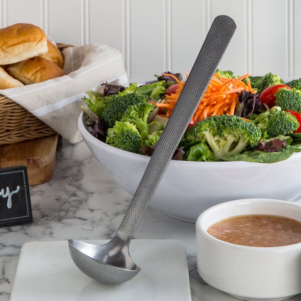 A bowl of soup with a hammered stainless steel ladle.