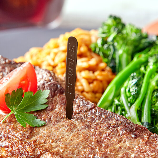 A steak with broccoli and beans on a plate with a Royal Paper Brown Medium Well Steak Marker.