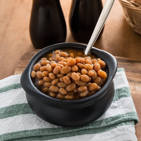 A bowl of beans with a spoon in a black Tuxton onion soup crock.