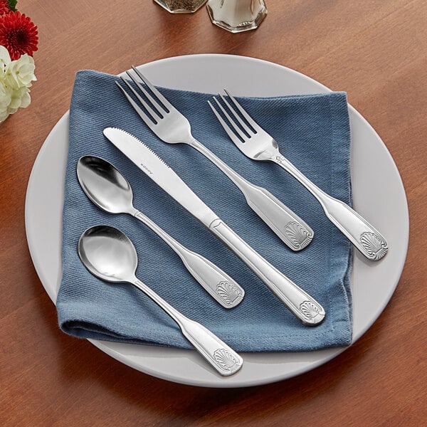 An Acopa Atglen 18/0 stainless steel medium weight flatware set on a blue cloth with a spoon and knife.