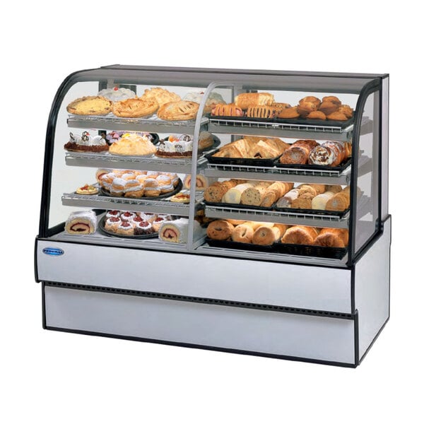 A Federal Industries curved glass dual zone refrigerated bakery case on a counter displaying various types of pastries.