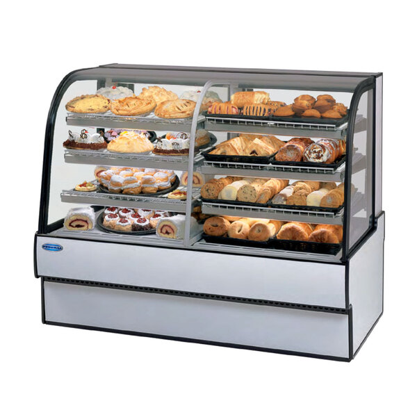 A Federal Industries curved glass dual zone refrigerated bakery case on a counter with different types of pastries inside.