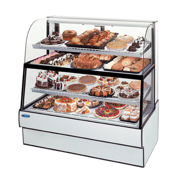 A Federal Industries curved glass dual-zone bakery display case full of pastries on a counter.