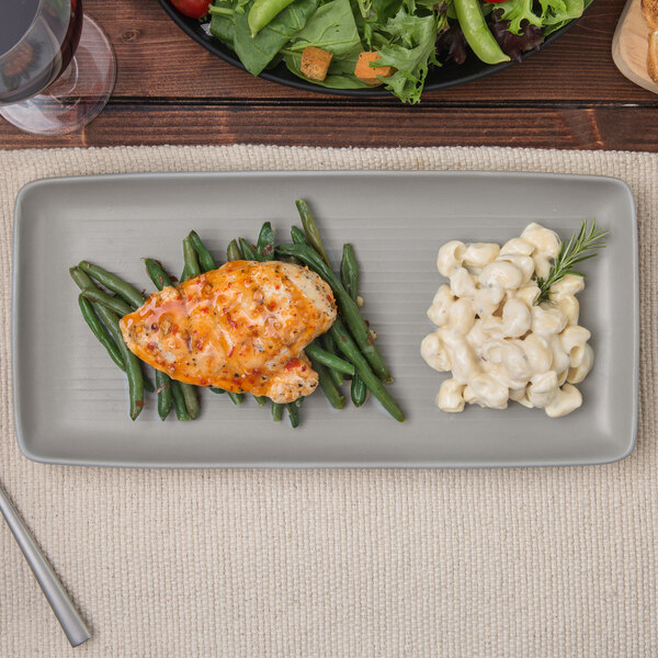 A TuxTrendz matte gray china tray with chicken, green beans, and macaroni on a table.