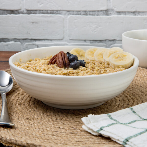 A TuxTrendz Zion matte white china bowl filled with oatmeal, bananas, and pecans.