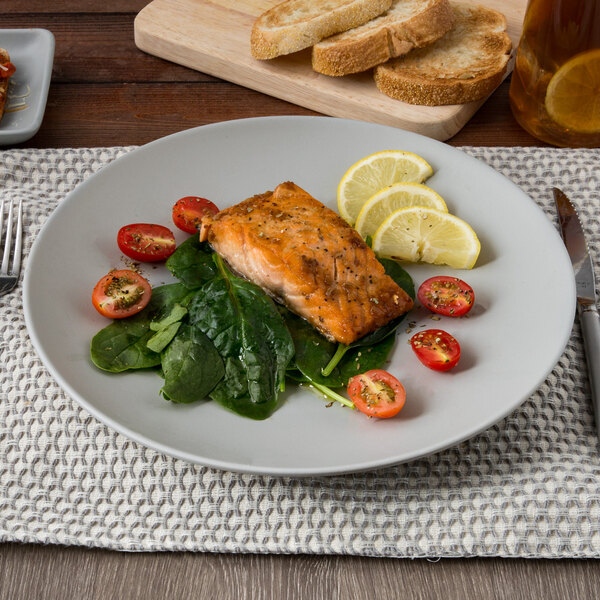 A TuxTrendz Zion Matte Gray china plate with salmon, spinach, and tomatoes on a table with a placemat.