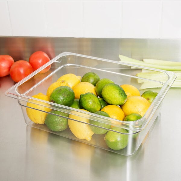 A clear plastic container with lemons and limes inside.