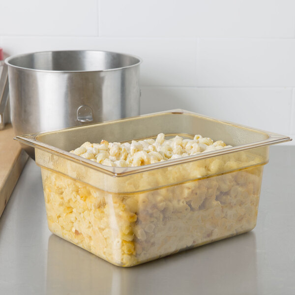 A Carlisle amber plastic food pan filled with food on a counter.
