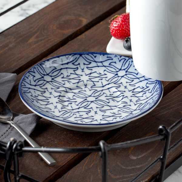 A Schonwald dark blue porcelain saucer with a color gradient pattern on a table with a spoon and a strawberry.