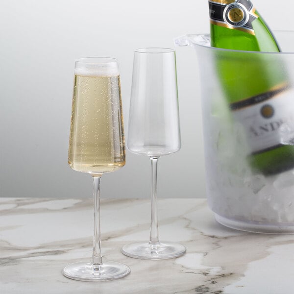 A pair of Stolzle flute glasses filled with champagne on a table.