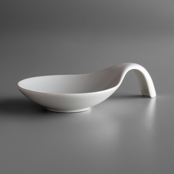 A Schonwald white porcelain spoon-shaped bowl on a grey surface.