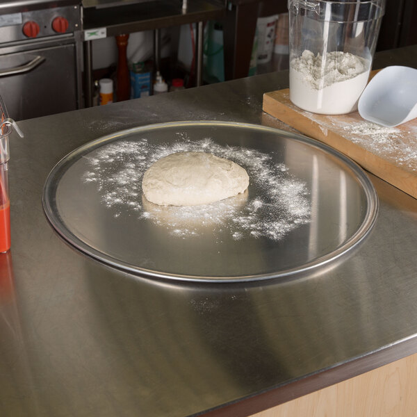 American Metalcraft aluminum coupe pizza pan with dough on it.
