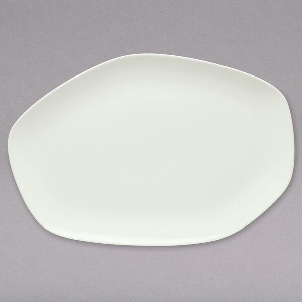 A Schonwald bone white porcelain oval coupe platter on a gray surface.