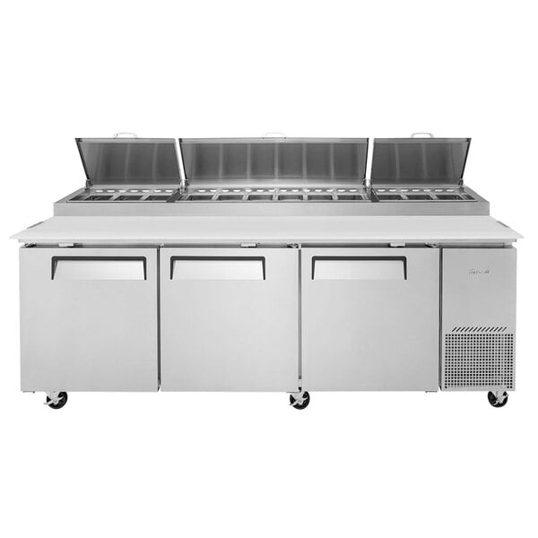 A Turbo Air refrigerated pizza prep table with three doors on a counter.