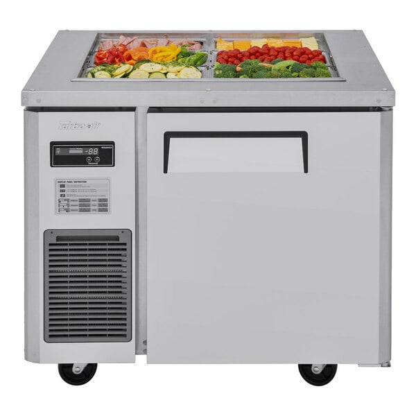 A Turbo Air stainless steel refrigerated buffet table with food trays of vegetables in it.