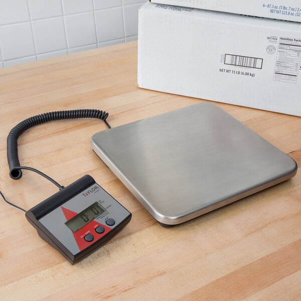 A Taylor digital receiving scale with a cord attached to it on a wood surface.