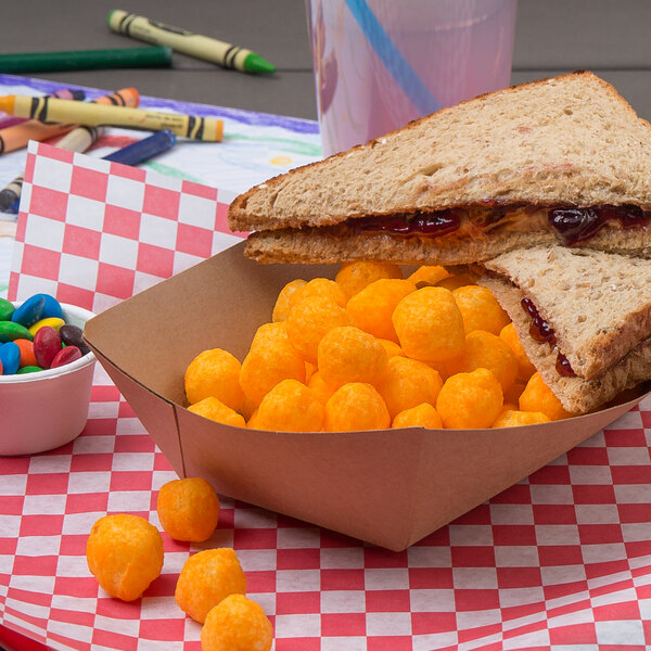 A sandwich and Martin's cheese balls in a paper bowl on a table.