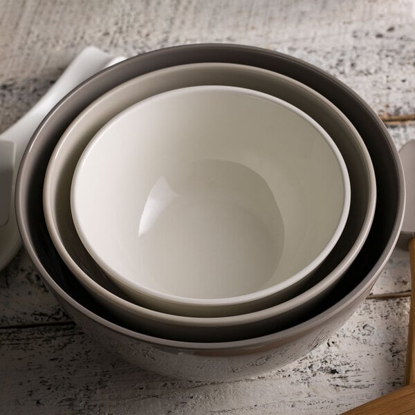 A stack of Tablecraft Crofthouse melamine mixing bowls with a spoon on top.