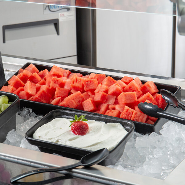 A G.E.T. Enterprises Bugambilia black rectangular salad bowl filled with watermelon cubes on a hospital cafeteria counter.