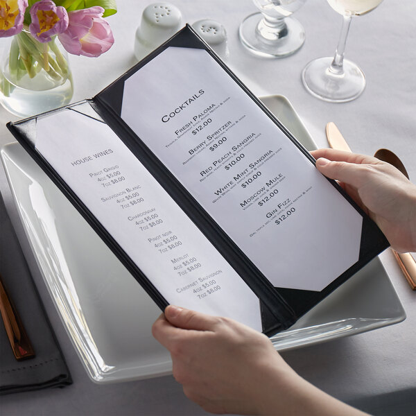 A person holding a H. Risch, Inc. Oakmont menu cover on a plate on a table in a fine dining restaurant.