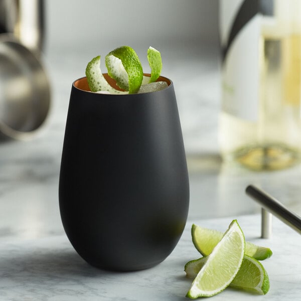 A matte black Stolzle stemless wine glass filled with lime slices.