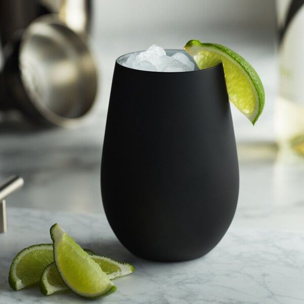 A Stolzle matte black stemless wine glass with ice and lime wedges.