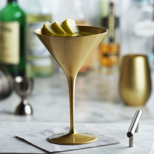 A Stolzle gold martini glass with a slice of apple in it.