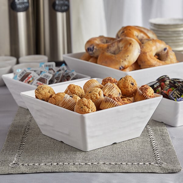 A white American Metalcraft faux slate melamine serving bowl on a table with a variety of pastries and coffee.