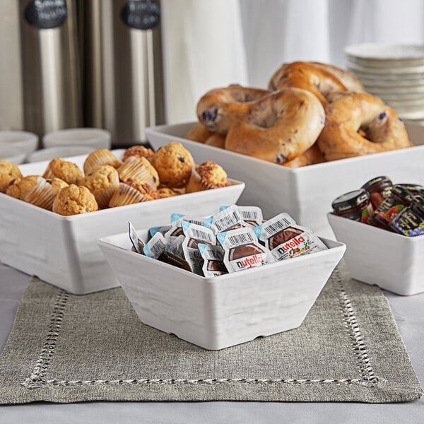 A white American Metalcraft melamine serving bowl on a table with a variety of pastries.