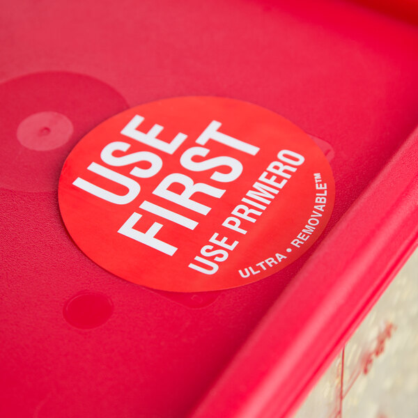 A red container with a round white sticker with the words "Use First" on it.