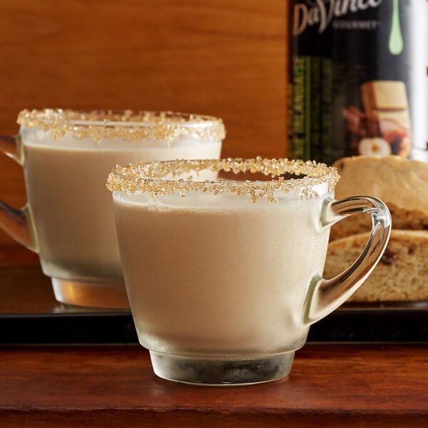 A glass of white liquid with a brown sugar rim next to a glass of DaVinci Gourmet Classic Irish Cream flavoring syrup.