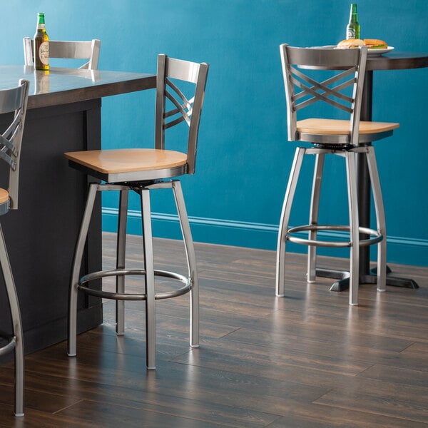 A Lancaster Table & Seating bar stool with a wooden back and metal frame.