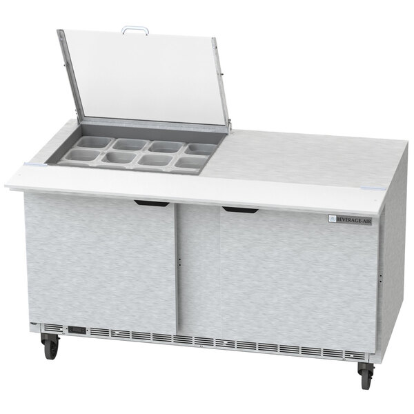 A Beverage-Air commercial sandwich prep table with two doors open over plastic trays with holes.