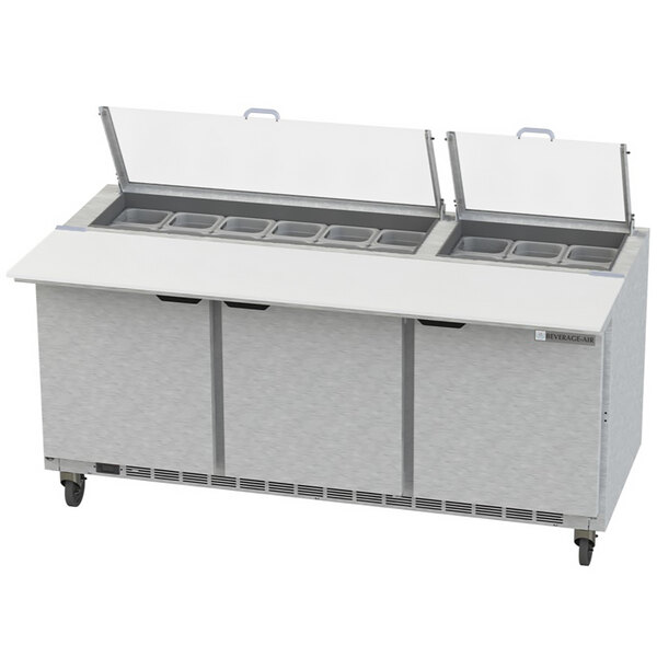 A Beverage-Air stainless steel 3 door refrigerated sandwich prep table with clear lids on a counter.
