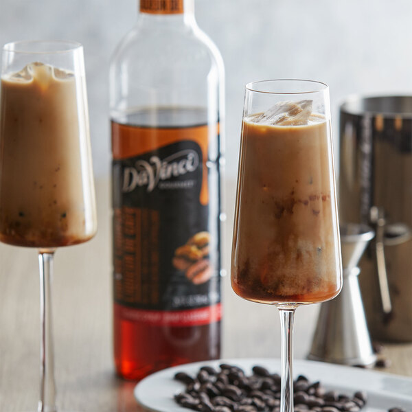 Two glasses of coffee with ice and DaVinci Gourmet Classic Coffee Liqueur Flavoring Syrup on a table.