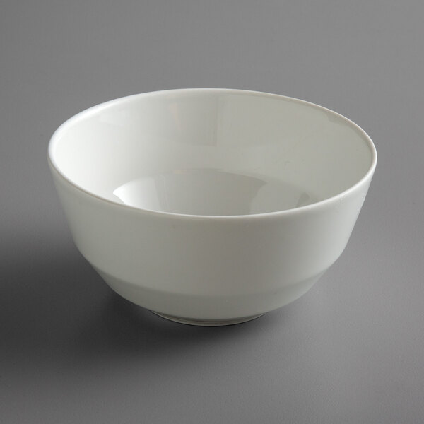 A Schonwald bone white porcelain bowl with a white rim on a gray surface.