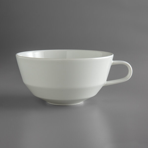 A Schonwald bone white porcelain cafe au lait cup with a handle on a gray surface.