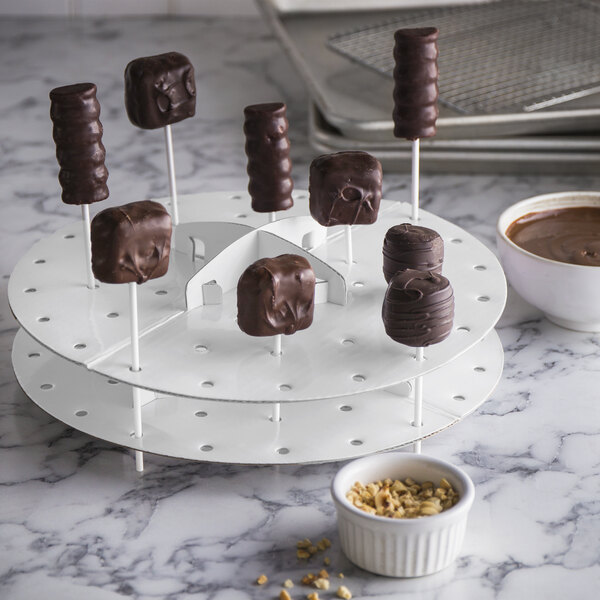A Wilton cake pop stand holding chocolate covered marshmallows.