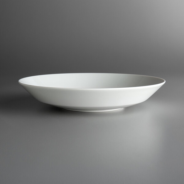 A Schonwald Allure bone white porcelain deep coupe bowl on a gray surface.